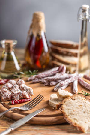 Set of salami sausages served with red hot chili peppers on wooden cutting boardの写真素材