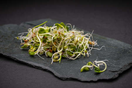 Heap of fresh sprouts on black slate surfaceの写真素材