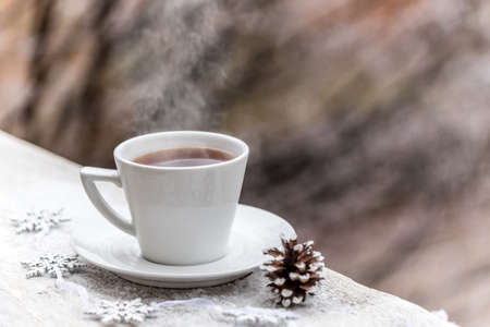 Hot drink in the cup on snow-capped wooden tableの写真素材