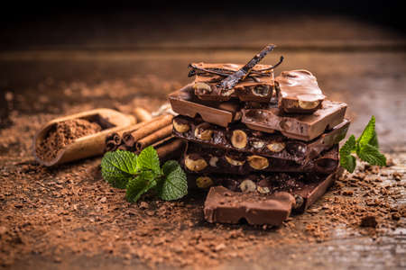 Broken chocolate bar and spices on wooden tableの写真素材