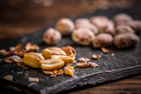 Roasted and salted peanuts on black slate board