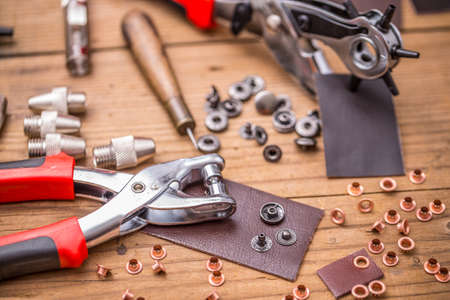 Leather punch tools with accessories on wooden board
