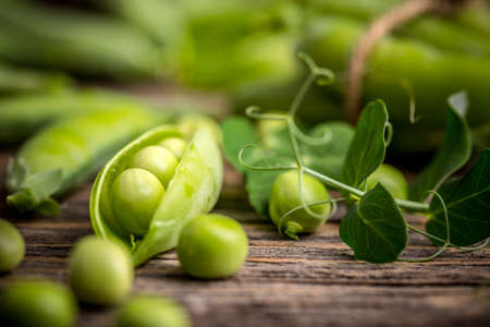 Hearthy fresh green peas and pods on rustic wooden backgroundの写真素材