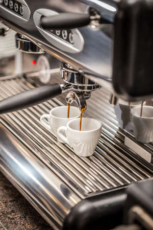 Professional espresso machine pouring strong looking fresh coffee into a ceramic cupの写真素材