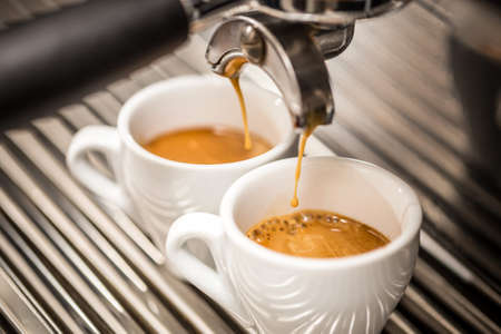 Espresso machine pouring coffee in white cupsの写真素材