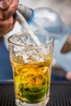Bartender pours soda water in mojito cocktailの写真素材