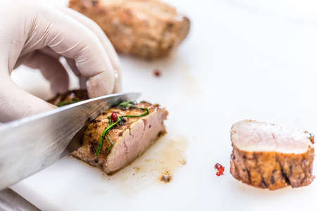 Chef cuts loin pork meat for fine dining plateの写真素材