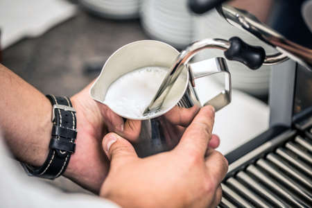Barista steaming milk for hot cappuccino with machineの写真素材