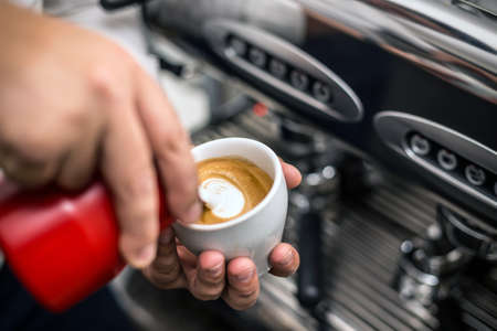 Barista preparing proper cappuccino pouring milk froth in a cupの写真素材