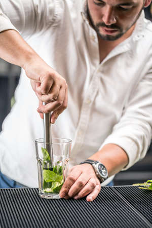 Bartender mashed with a muddler mint leaf and lime for mojito cocktail