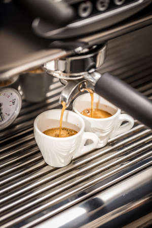 Espresso machine pouring coffee in white cupsの写真素材