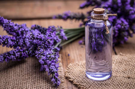 Lavender oil in a glass bottle on a background of fresh flowersの写真素材