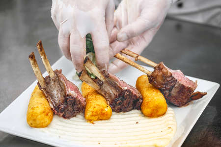 Lamb ribs served on white plate with mashed potato-filled croquettesの写真素材