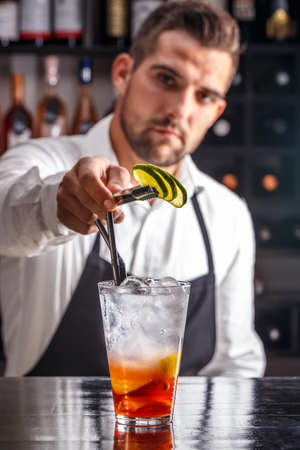 Barman decorating cocktail with limeの写真素材