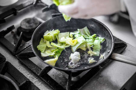 Chef adding chopped iceberg lettuce to a panの写真素材