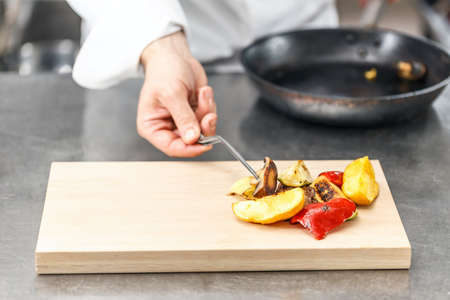 Chef serving delicious grilled vegetable on wooden bboardの写真素材