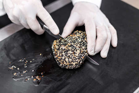 Chef cutting roasted tuna steaks crusted with sesame seeds
