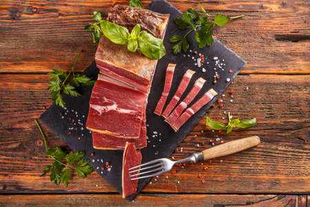 Slice of prosciutto or jamon with herbs and spicesの写真素材