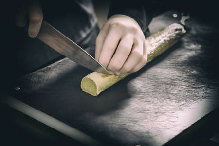 Chef cutting compound butter on black cutting boardの写真素材