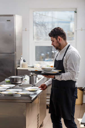Young waiter wearing apron, ready to serve lunchの写真素材