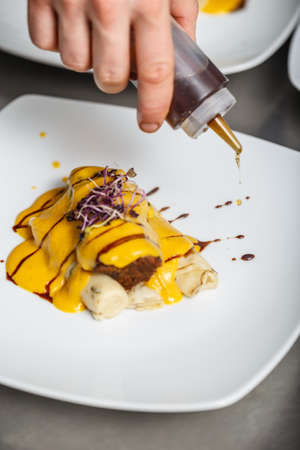 Chef decorate a dish, pour the sauceの写真素材
