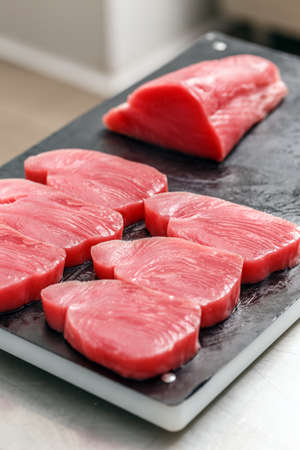 Raw tuna steak on black cutting boardの写真素材