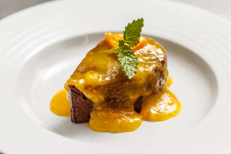 Chocolate cake with orange sauce decorated with mint leafの写真素材