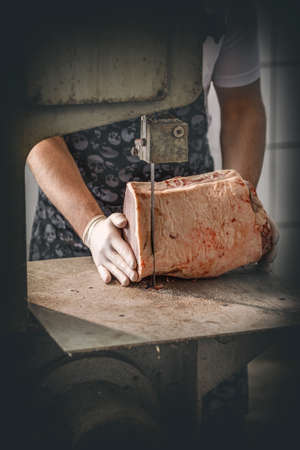 Butcher is cutting beef meat with big electric saw at the meat manufacturingの写真素材
