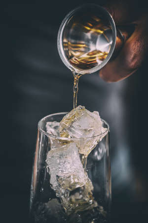Bartender pouring alcohol in glass, close up shotの写真素材