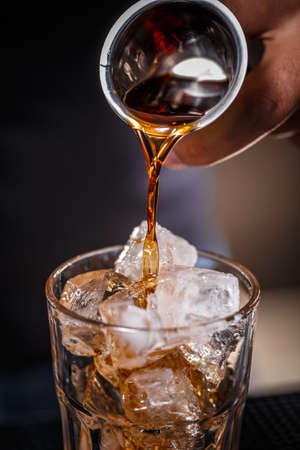 Bartender pouring alcohol in glass, close up shotの写真素材