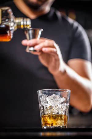 Bartender at work in bar pouring drink into measuring glassの写真素材