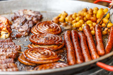 Different smoked pork sausages with whole potato in big frying pan