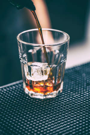 Bartender pours alcoholic drink into glass