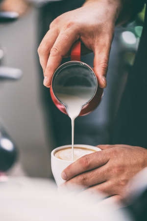 Close up of barista adding milk to coffeeの写真素材
