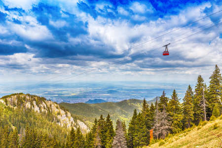 Red cable car way to mountains moving down in Poiana Brasov, Romaniaの写真素材