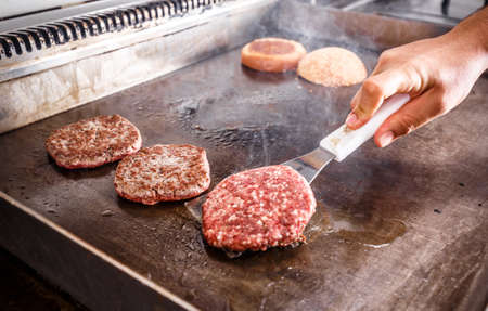 Chef cook frying meat for hamburger in restaurant kitchenの写真素材
