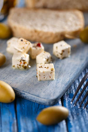 Little cubes of cheese over blue wooden backgroundの写真素材