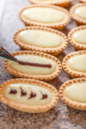 Woman hand decorating mini tarts, close upの写真素材