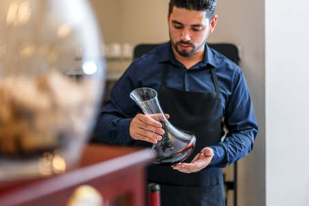 Waiter hold bottle of red wine in restaurantの写真素材