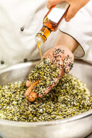 The chef prepares pumpkin seeds, linseed and sunflower seed ingredients for saladの写真素材