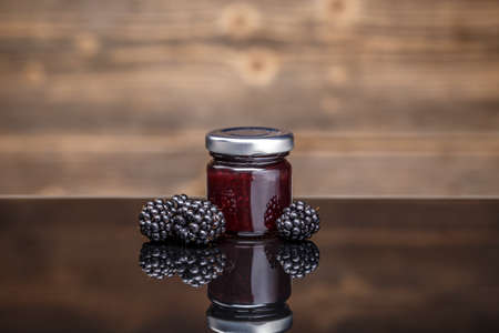 Fresh homemade blackberry jam in glass jar with some fresh fruitsの写真素材