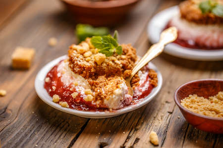 Delicious cheesecake dessert with strawberry sauce on wooden backgroundの写真素材