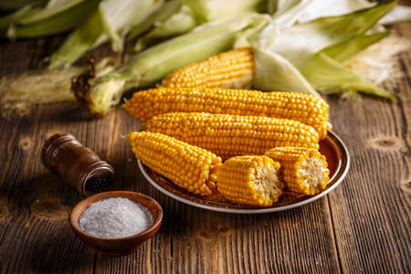 Boiled corn on a plate in the wooden boardの写真素材