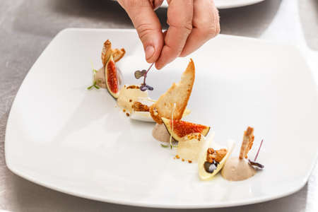 Chef finishes his plate and almost ready to serve at the tableの写真素材