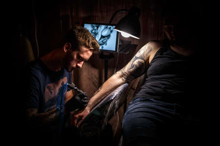 Image of the bearded tattoo male artist makes a tattoo on a man hand.の写真素材
