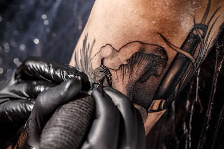 Hands of professional artist making tattoo in salon, close up viewの写真素材