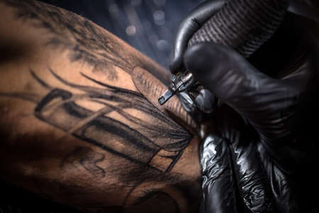 Tattoo master works in black sterile glovesの写真素材