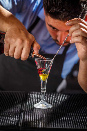 Bartender preparing layered cocktail on bar counterの写真素材