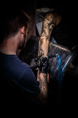 Master tattoo draws the black paint on the clients tattoo.の写真素材