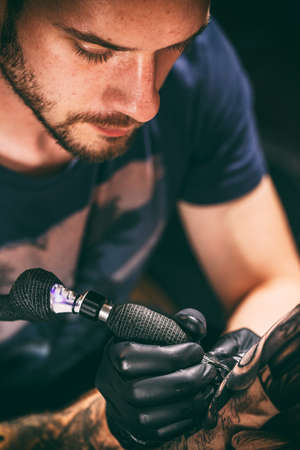 Image of the bearded tattoo male artist makes a tattoo on a man hand.の写真素材